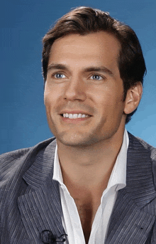 a man wearing a suit and a white shirt smiles for the camera