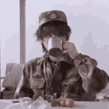 a person in a military uniform is drinking from a mug