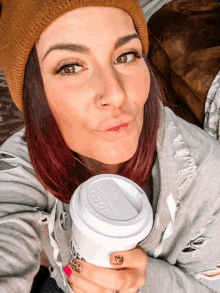 a woman wearing a beanie and holding a cup that says solo on it