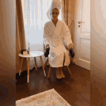 a woman in a bathrobe is sitting in a chair