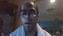 a bald man wearing glasses and a white towel around his neck