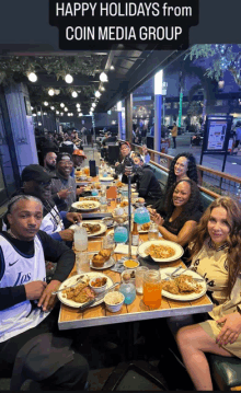 a group of people are sitting at a table with plates of food and drinks with the words happy holidays from coin media group written above them