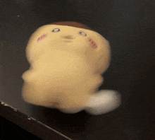 a stuffed animal with a face on it is sitting on a black surface
