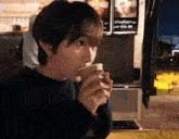 a woman drinking from a cup with a sign behind her that says ' a ' on it