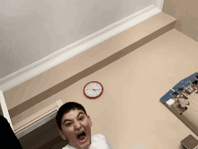 a boy screams in front of a wall clock that shows the time as 7:20