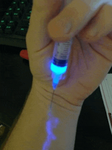 a person is holding a syringe that has a blue light on it