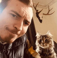 a man and a cat are posing for a picture in front of antlers