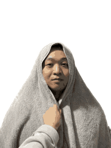 a man is wrapped in a gray towel with a hand holding it