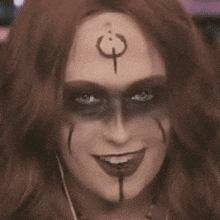 a woman with makeup on her face has a symbol on her forehead .