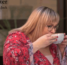 a woman drinking a cup of coffee in front of a sign that says ' ter jack ' on it