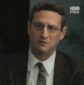 a man in a suit and tie with a hbo max advertisement in the background