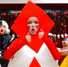 a woman in a red and white costume with hearts painted on her face is giving a thumbs up .