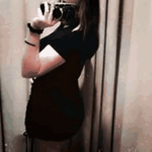 a woman is taking a picture of herself in a dressing room with a camera .