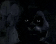 a black cat with glowing eyes is standing in the dark .