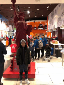 a boy is standing in front of a statue of liberty