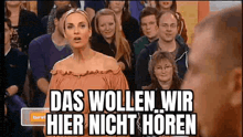 a woman is standing in front of a crowd of people with the words das wollen wir hier nicht horen .