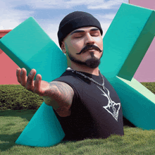 a man with a beard and mustache is meditating in front of a large green x