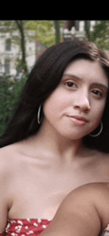 a close up of a woman 's face with a red dress and hoop earrings