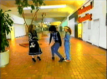 a group of people are dancing in a mall with a sign that says hollywood