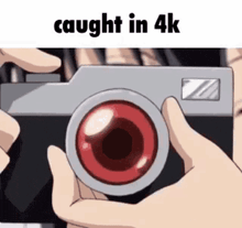 a person is holding a camera with a red lens and the words `` caught in 4k '' below it .