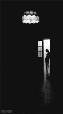 a black and white photo of a woman standing in a dark room