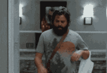 a man with a beard is standing in a hallway with a towel around his shoulder .