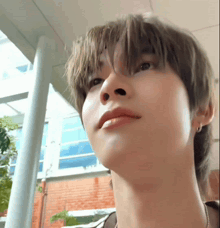 a close up of a young man 's face with a brick building in the background .