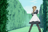 a girl in a maid outfit stands in front of a green hedge