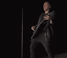 a man in a black jacket is playing a guitar