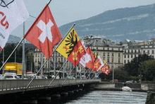 a row of flags are flying on a bridge in front of a building that says rolex