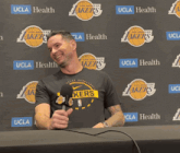 a man holding a microphone in front of a wall that says lakers