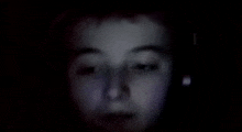 a close up of a child 's face in the dark with headphones on