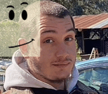 a man wearing a hoodie has a smiley face drawn on his face