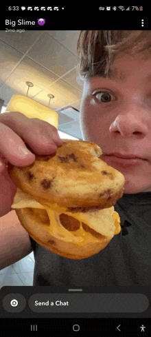 a young man is holding a sandwich in front of his face with the words big slime on the bottom right