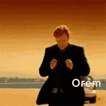 a man in a suit is standing in front of a car in the desert with the word orem written on the bottom .