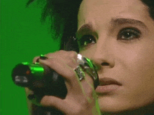 a close up of a woman holding a microphone in front of a green background .