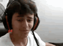 a young boy wearing headphones is sitting in front of a computer screen .