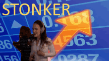 a woman wearing headphones is standing in front of a screen that says stonker