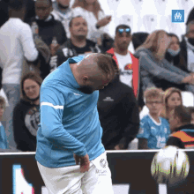 a man in a blue shirt is standing in front of a soccer ball with the word om on it