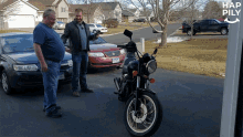 two men standing next to a motorcycle with a car in the background and hap pily written on the bottom