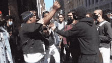 a group of people are standing on a street and one of them is wearing a black hoodie