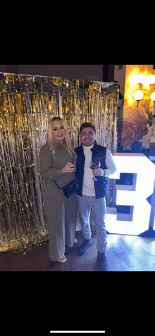 a man and a woman standing in front of a large white number 3