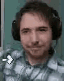 a man wearing headphones and a plaid shirt is smiling and winking .