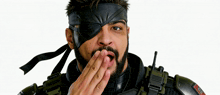 a man with a beard wearing a black eye patch covering his mouth with his hand