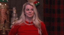 a woman wearing a red sweater and a necklace with pearls on it