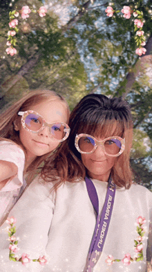 a woman and a little girl wearing sunglasses and a lanyard that says ' bloomia festival '