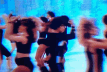 a blurry photo of a group of people dancing in front of a blue background