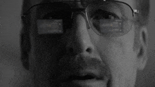 a close up of a man wearing glasses with a reflection of a screen