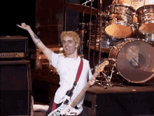 a man playing a guitar in front of a drum set with a sticker that says ' green day ' on it