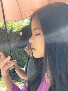 a woman in a purple shirt holds an umbrella